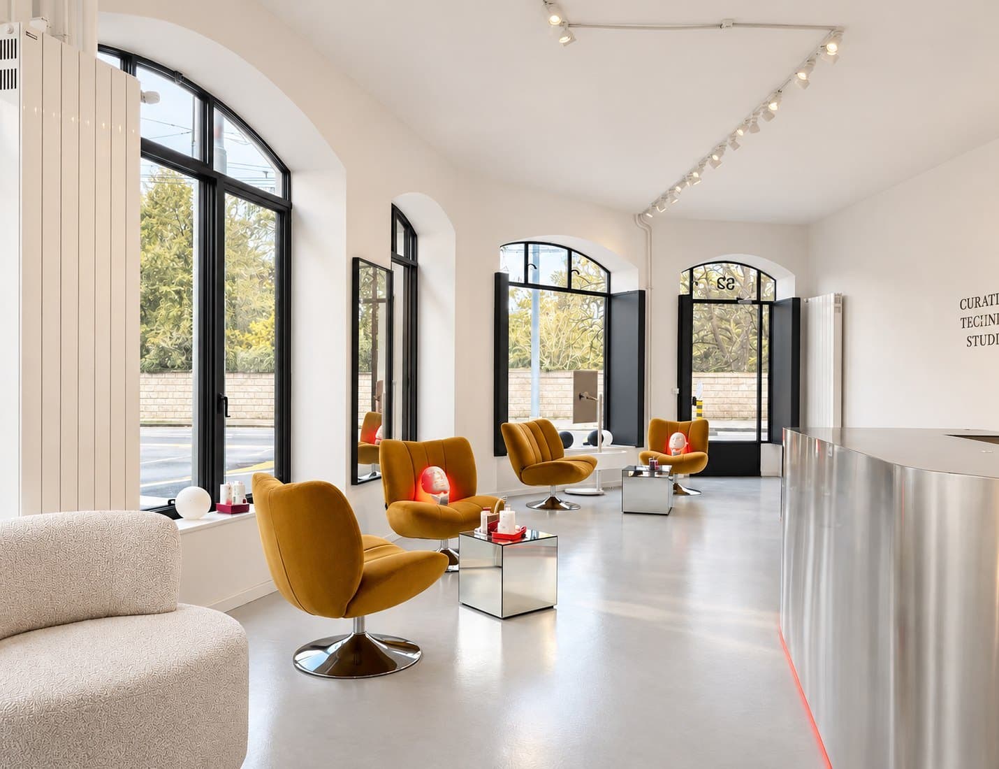Vue d'ensemble du studio Cura Tech, fauteuils moutarde et fenêtres en arche